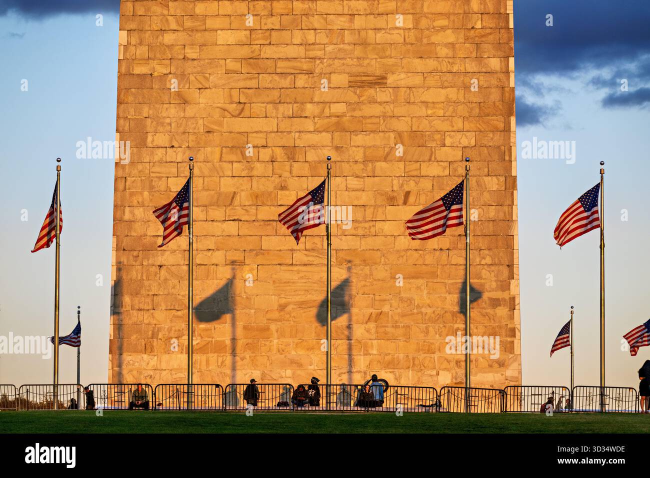 Washington Monument con bandiere alla luce del sole nel tardo pomeriggio Washington DC // WASHINGTON DC — il Washington Monument, un iconico obelisco in onore del primo presidente degli Stati Uniti George Washington, si vede con bandiere americane che volano nelle vicinanze alla luce del sole nel tardo pomeriggio. Questo importante punto di riferimento sul National Mall, costruito in marmo, granito e gneiss di pietra blu, si erge a 169,29 metri (555 piedi e 1/8 pollici) di altezza. Costruita tra il 1848 e il 1884 e dedicata nel 1885, la sua sezione inferiore mostra una differenza di colore distinta dalla sua parte superiore, riflettendo le diverse cave utilizzate. Le ombre vengono proiettate attraverso i suoi Foto Stock
