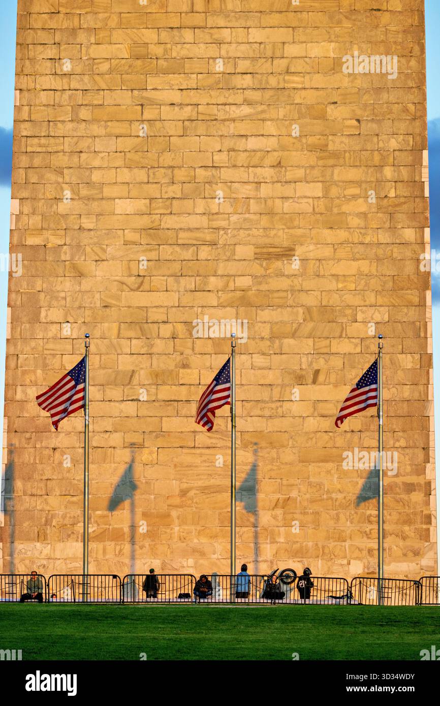 Monumento a Washington con bandiere e ombre Washington DC // WASHINGTON DC - il monumento a Washington è visto con tre bandiere americane che sventolano davanti alla sua base, gettando lunghe ombre alla luce del sole del tardo pomeriggio poco prima del tramonto. Questo iconico obelisco sul National Mall commemora George Washington, il primo presidente degli Stati Uniti. Alto 169,29 metri (555 piedi e 1/8 pollici), è costruito principalmente in marmo, granito e gneiss di pietra blu. La costruzione del monumento iniziò nel 1848 e fu completata nel 1884. Foto Stock