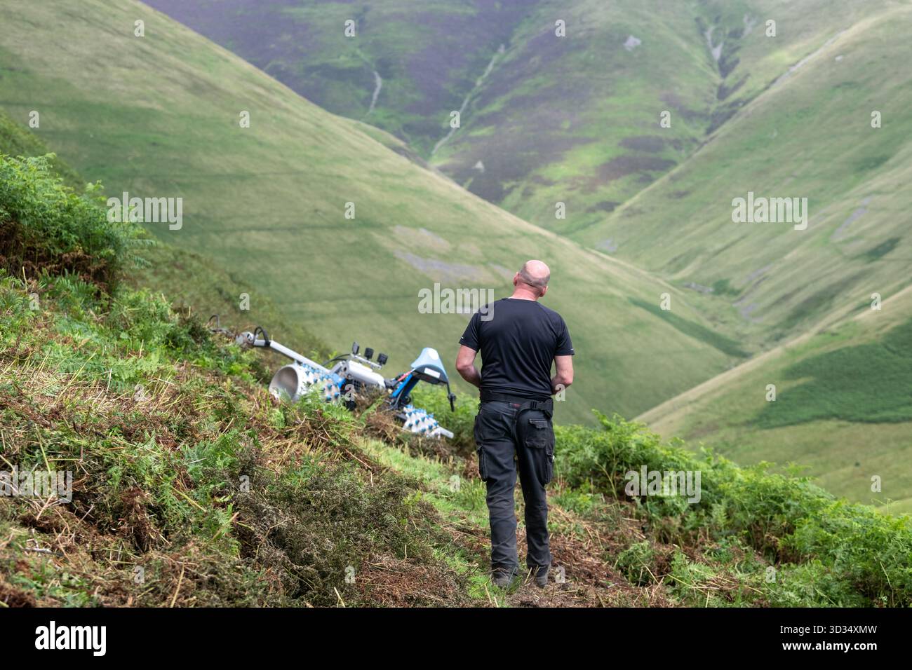 Agricoltore che utilizza un rasaerba telecomandato per tagliare Bracken su un pendio ripido, per controllare la diffusione dell'impianto invasivo. Howgill Fells in t Foto Stock