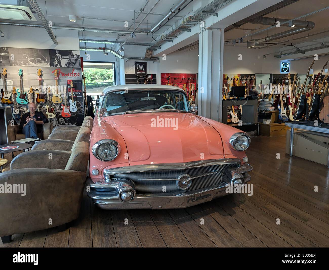 Colonia, Germania - 26 settembre 2025: Un'auto d'epoca rosa si trova all'interno di un negozio di musica, creando un'esibizione stravagante e accattivante che fonde il st. Retro Foto Stock