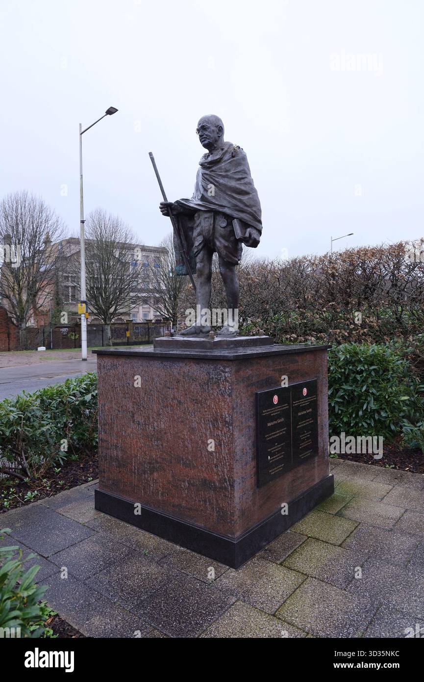 Statua di bronzo dell'icona della pace indiana Mahatma Gandhi vicino al Wales Millennium Centre nella baia di Cardiff. Tiene in mano la gita, il libro sacro indù. Foto Stock