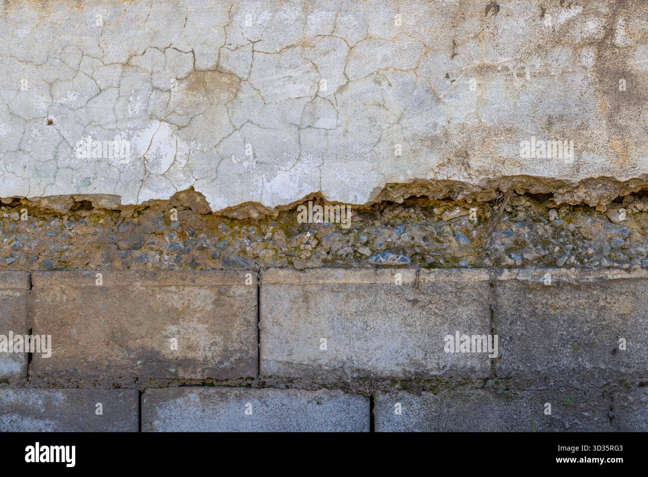 Pareti intonacate e in mattoni con agenti atmosferici che mostrano danni sotto la luce solare Foto Stock