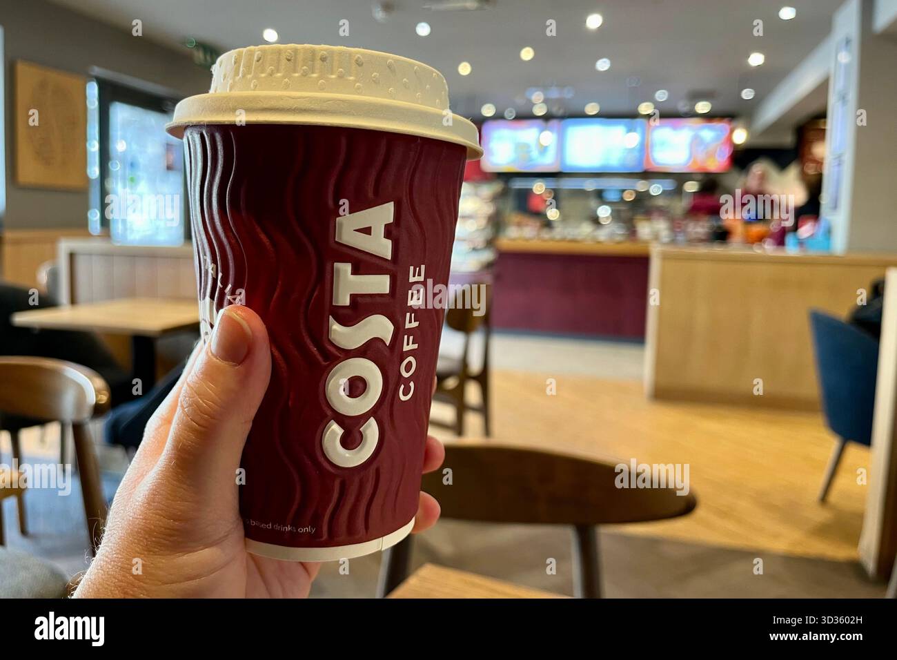 Tenere a mano Costa Coffee Cup all'interno di un locale Costa Coffee a Cowbridge. Vale of Glamorgan, Galles, Regno Unito. 17 ottobre 2025. - Immagine stock catturata con smartphone