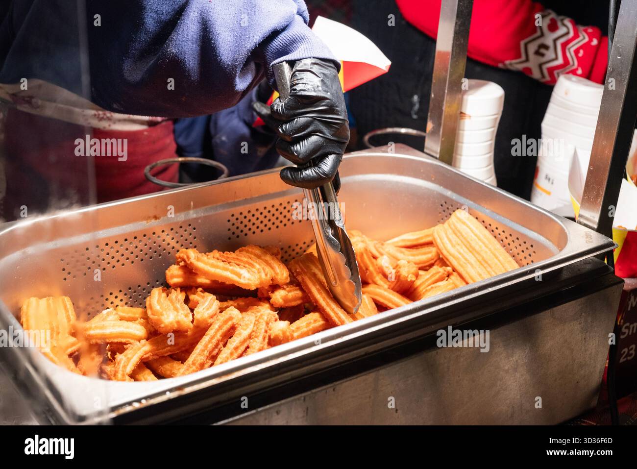 Preparare churros fritti di cibo di strada nel centro della città al mercatino di Natale di Cracovia, Polonia. Foto Stock