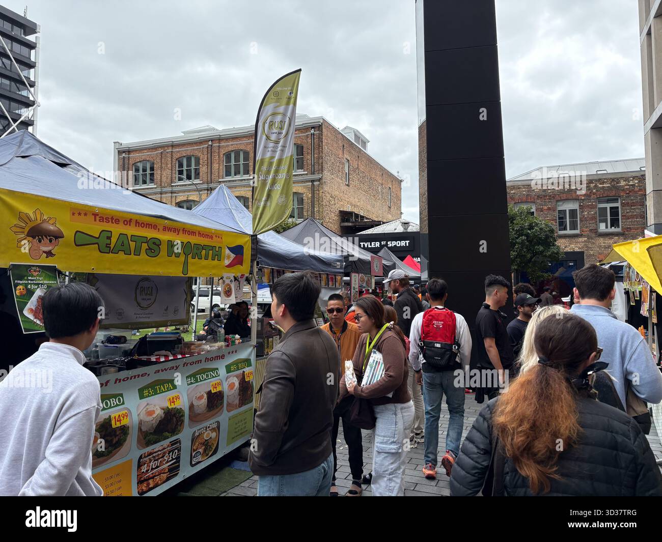 Mercato del sabato Britomart, Auckland. La gente curiosa tra diverse bancarelle di cibo, tra cui la cucina filippina, in questo vivace mercato all'aperto adagiato su un'urba Foto Stock