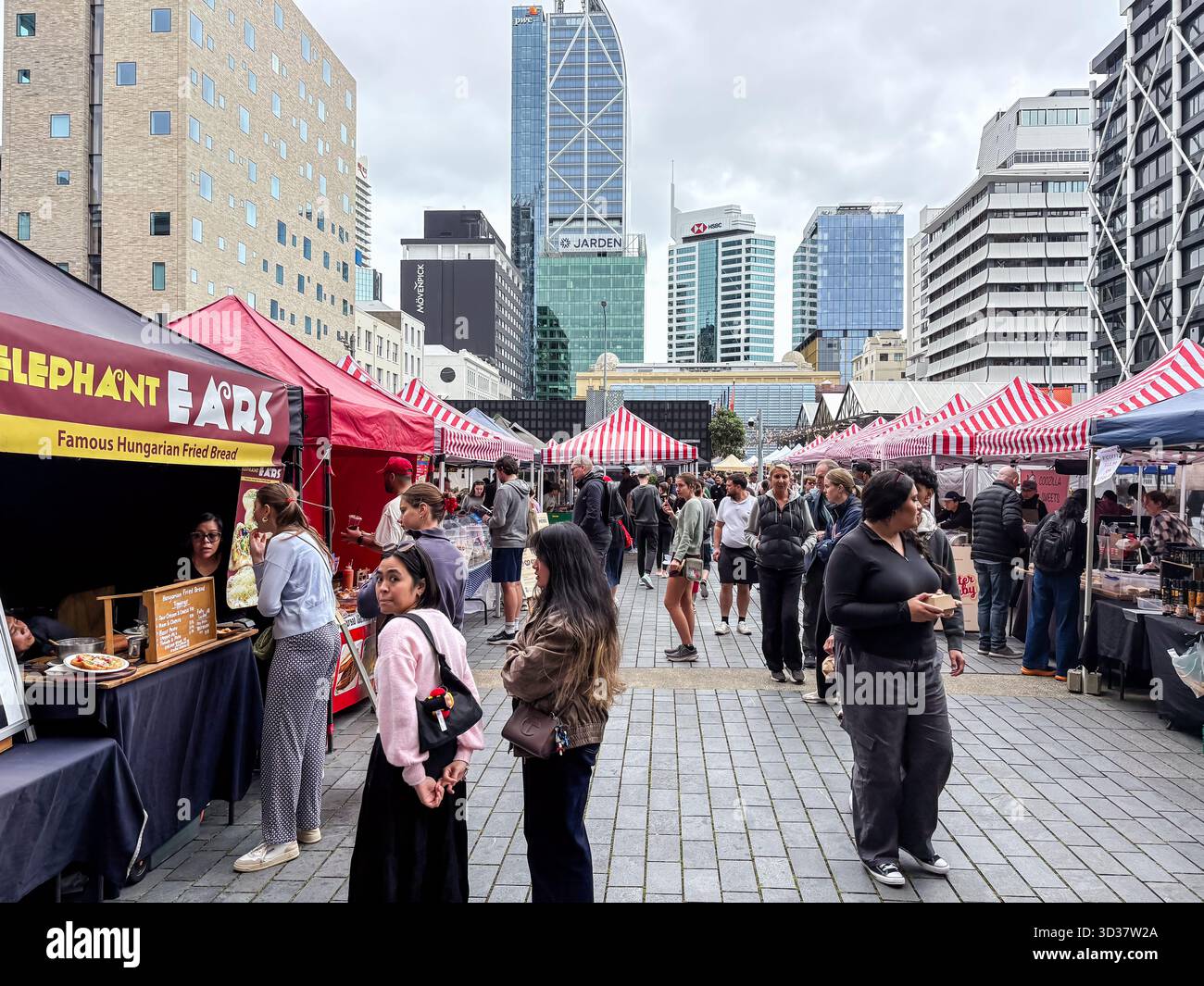 Mercato del sabato Britomart. Gli amanti dello shopping curiosano tra le bancarelle di cibo e artigianato sotto le tende rosse e bianche in un vivace mercato agricolo urbano. Città moderna Foto Stock