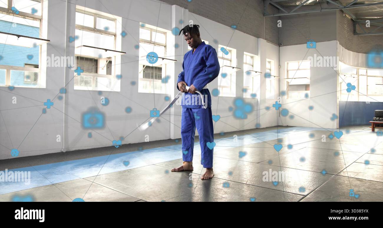 Artista marziale che indossa gi blu che regge la spada di legno nel dojo, con sovrapposizione digitale Foto Stock