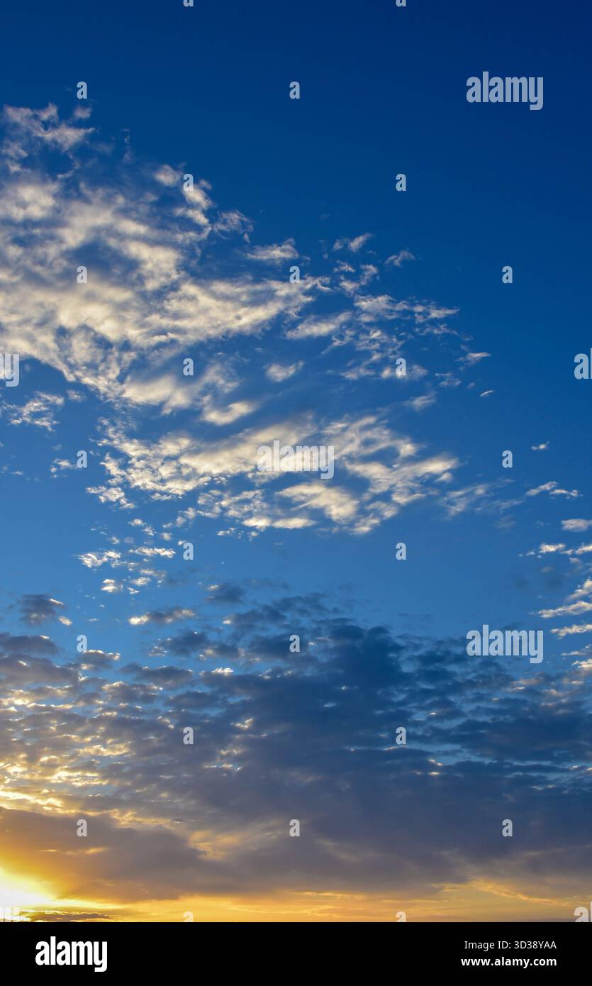 Cielo blu brillante con nuvole bianche sparse che fluttuano con grazia, catturando la freschezza e la purezza dell'atmosfera della luce del giorno. Foto Stock