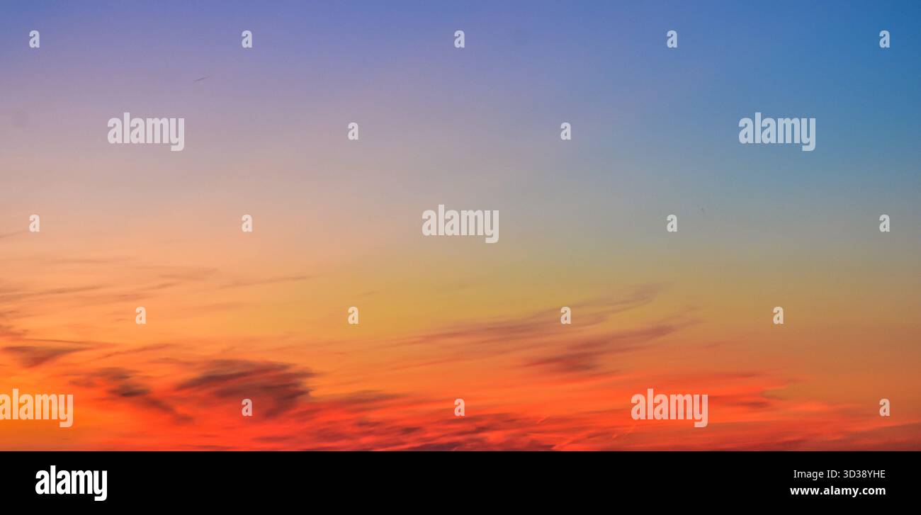 Il vivace cielo del tramonto è pieno di nuvole luccicanti in tonalità arancione, rosa e blu. Atmosfera tranquilla di bellezza naturale serale. Foto Stock