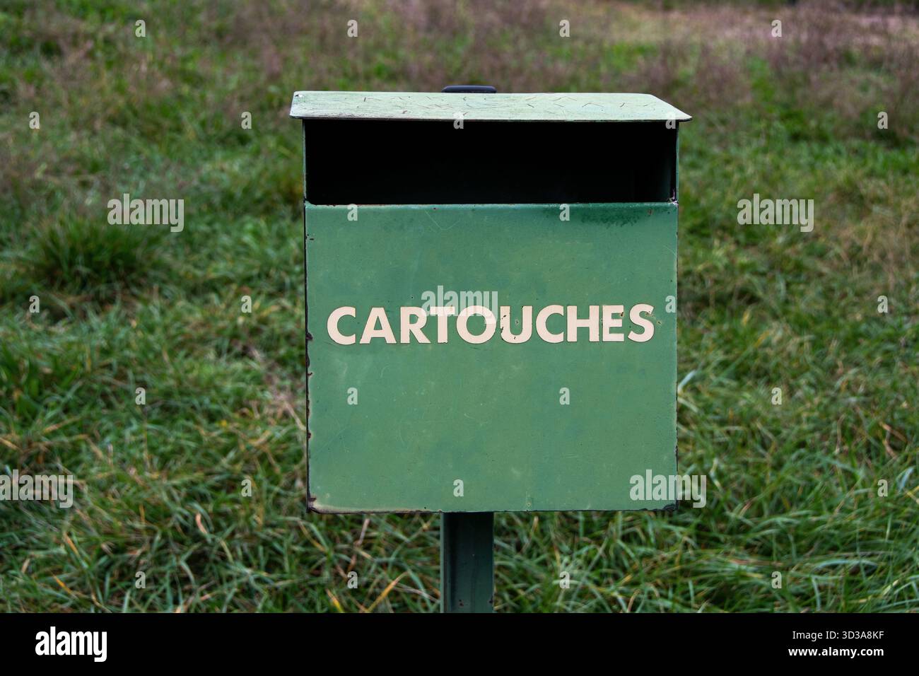 Una scatola di metallo verde con la parola "CARTIGLI" scritta per i cacciatori si erge su un palo in un campo erboso. Francia Foto Stock