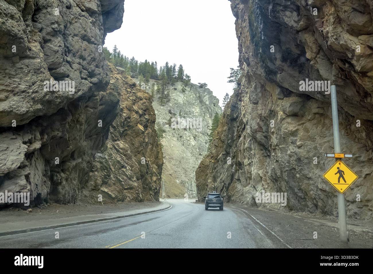 Radio, Columbia Britannica, Canada. 4 aprile 2025. Un'auto guida lungo un'autostrada scolpita attraverso un passo roccioso di montagna nella British Columbia, Canada. Un passaggio pedonale Foto Stock