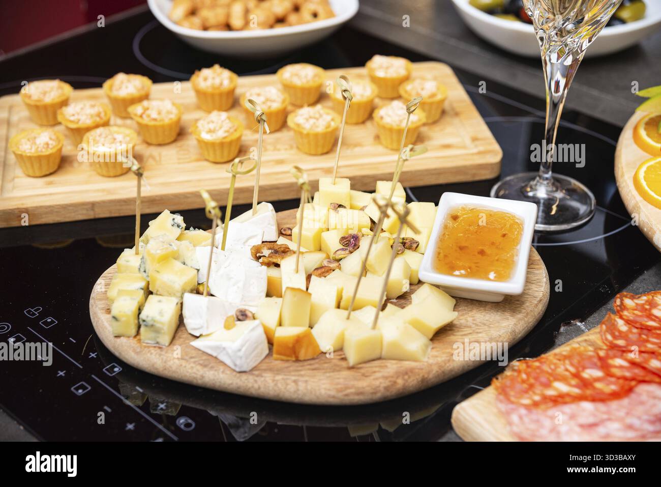 Cibo, piatto di formaggi assortiti con cubetti di vari formaggi, noci e marmellata dolce serviti su un tavolo di legno per antipasti o abbinamenti di vini Foto Stock