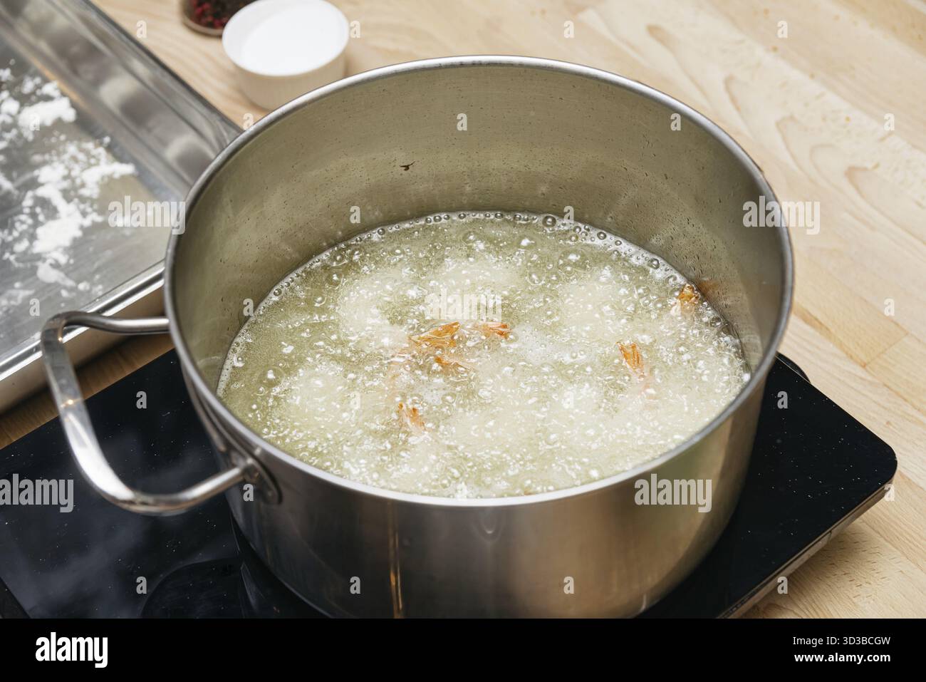 Cibo: I gamberetti vengono fritti in profondità in una grande pentola di olio bollente, mostrando una fase del processo di cottura o preparazione Foto Stock