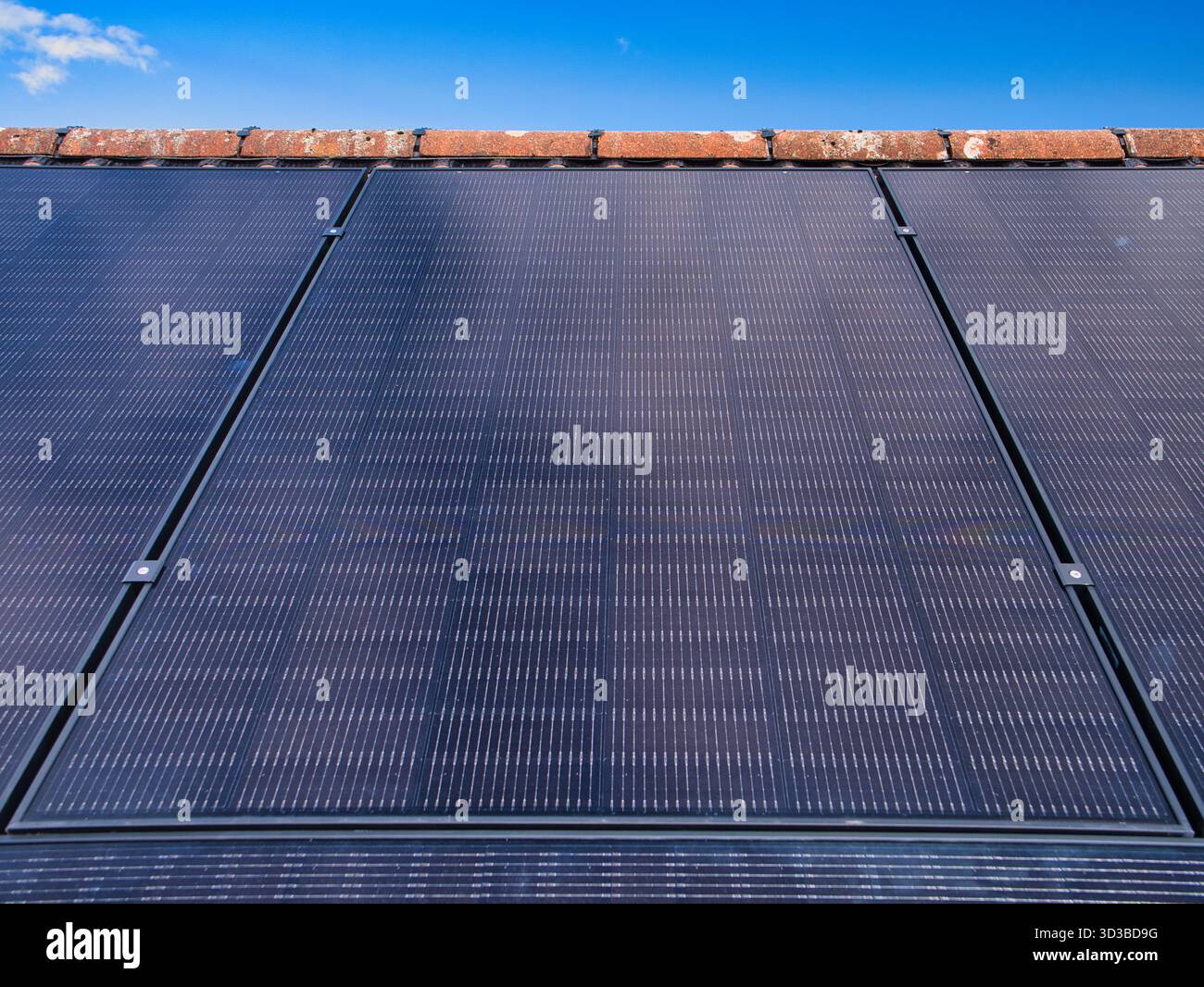 Primo piano di pannelli solari residenziali sul tetto di una casa sotto un cielo blu chiaro nel Regno Unito, catturando energia pulita e l'efficienza della casa moderna. Foto Stock