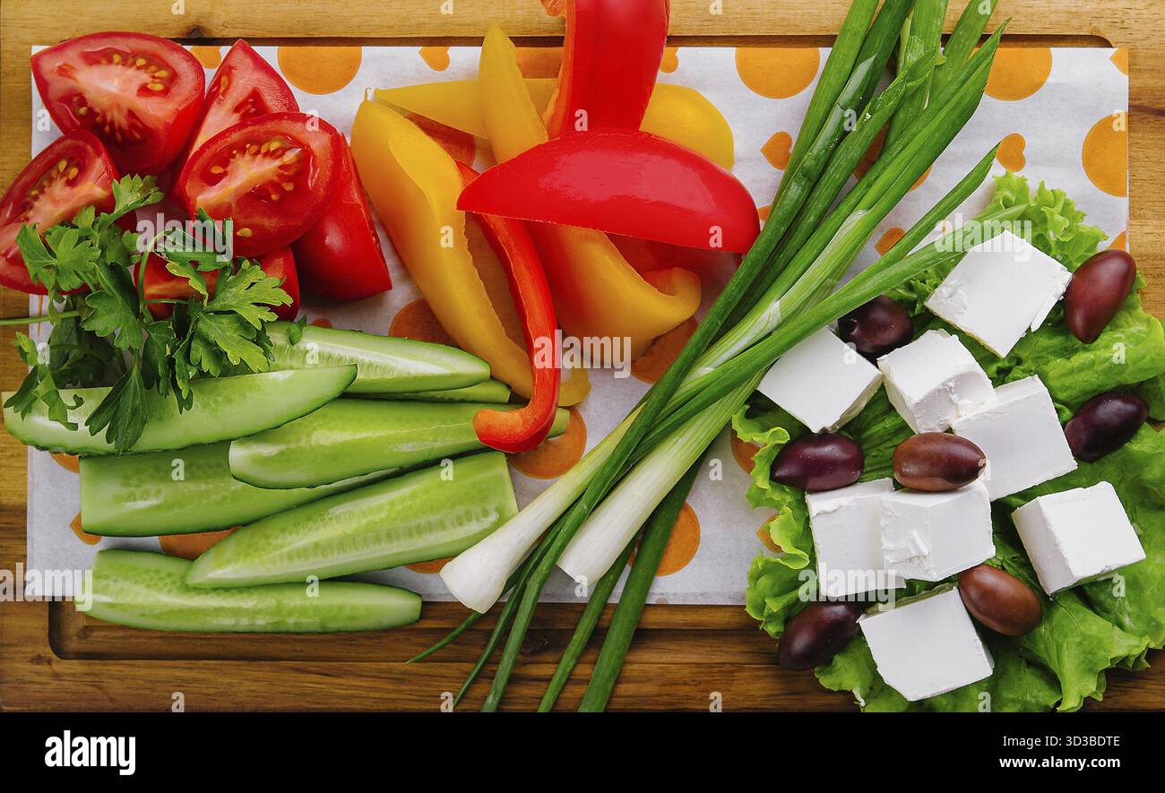 Cibo, cipolle, cetrioli, peperoni, pomodori e formaggio feta con olive su un vassoio di legno Foto Stock