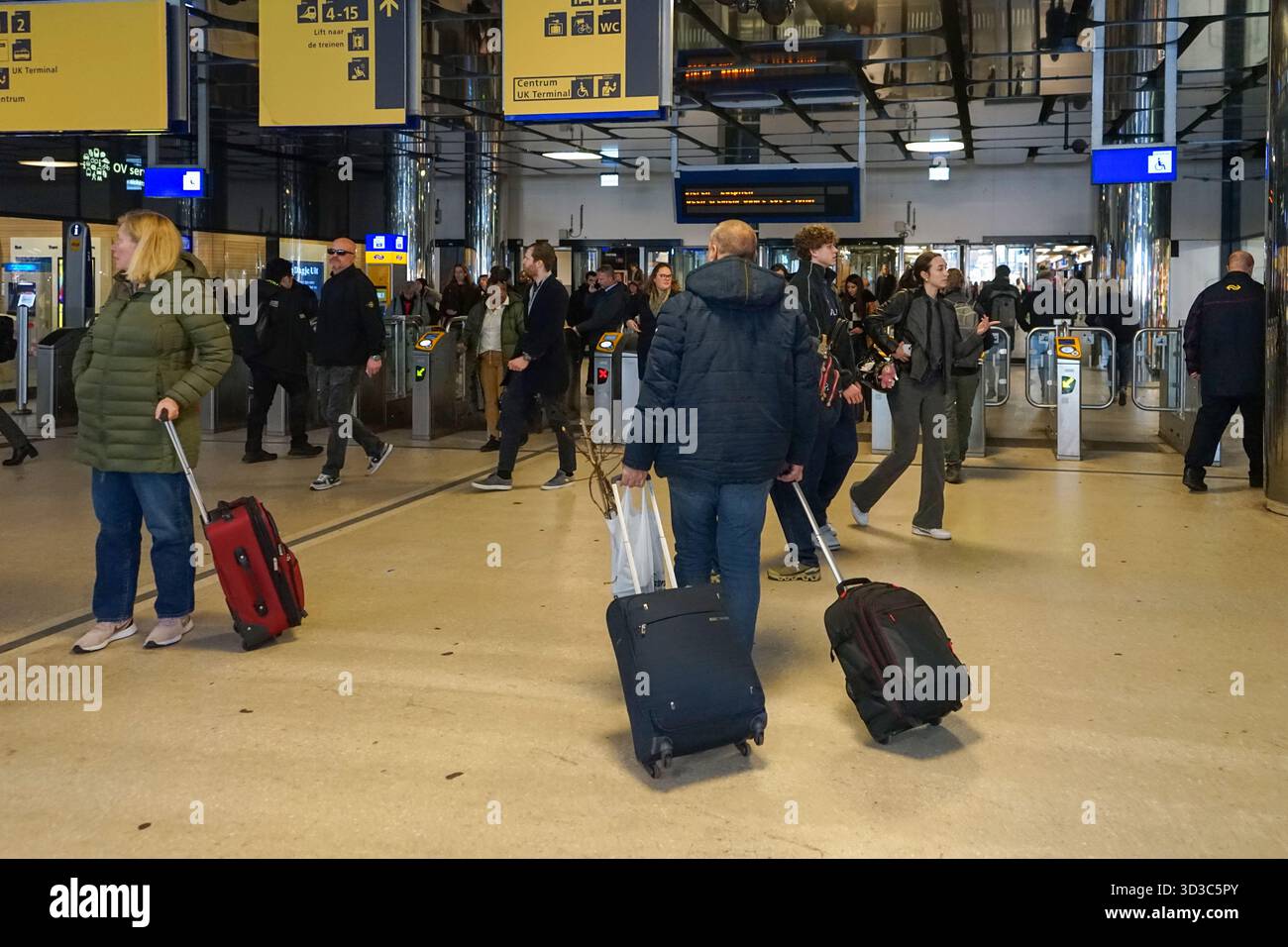 I viaggiatori passano attraverso le biglietterie nella sala principale della stazione centrale di Amsterdam, uno dei terminal ferroviari più trafficati d'Europa. Foto Stock