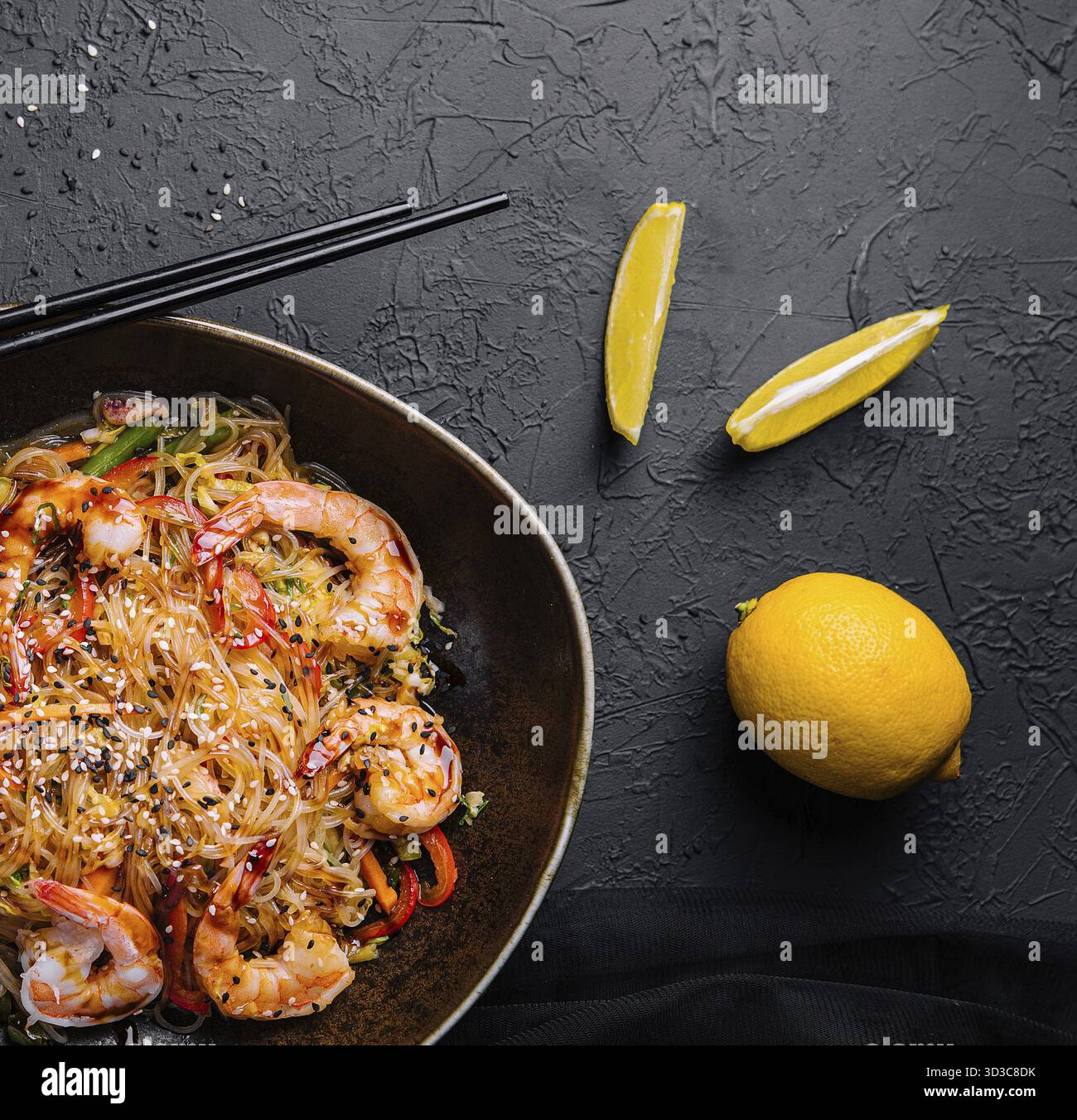 Cibo, mescolare gli spaghetti con verdure e gamberetti nel recipiente nero Foto Stock