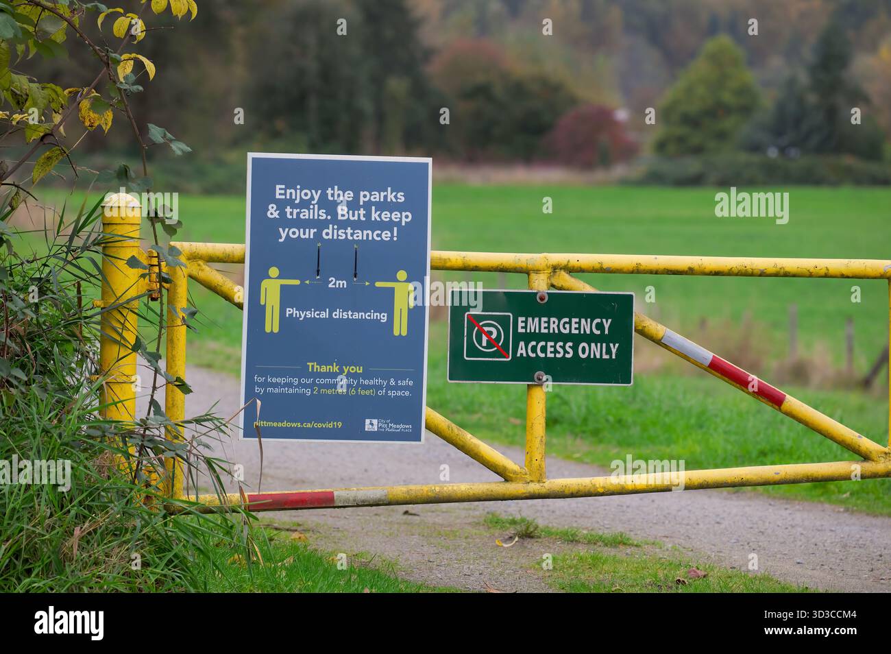 Cancello di accesso di emergenza a un sentiero di diga a Pitt Meadows, B. C., Canada durante il Covid 19 con un cartello che avvisa le persone di mantenere la loro distanza. Foto Stock