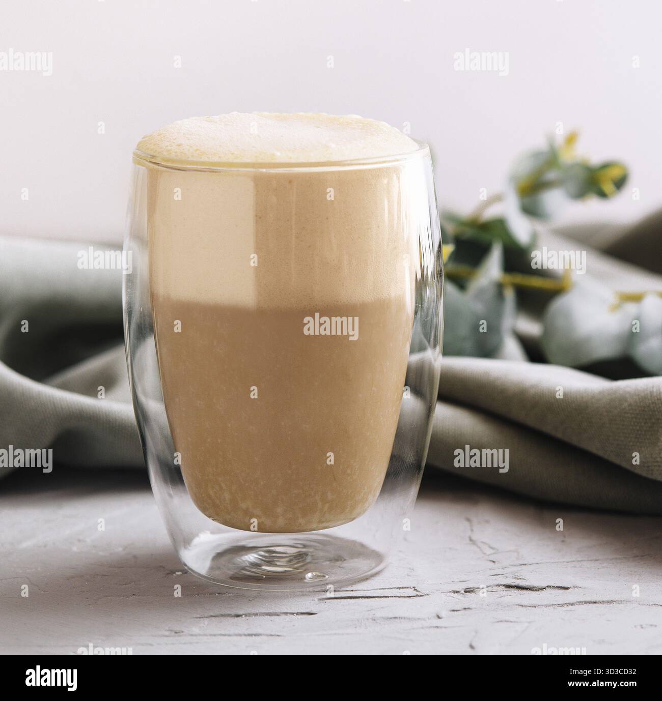 Tazza in vetro a doppia parete resistente al calore, riempita di latte o cappuccino Foto Stock