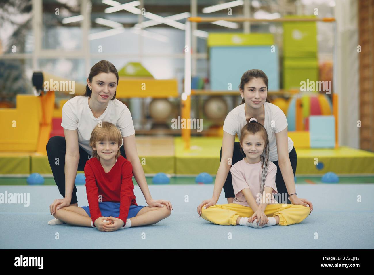 Bambini ragazza e ragazzo che fanno esercizi di stretching in palestra all'asilo o scuola elementare. Concetto di sport e fitness per bambini Foto Stock