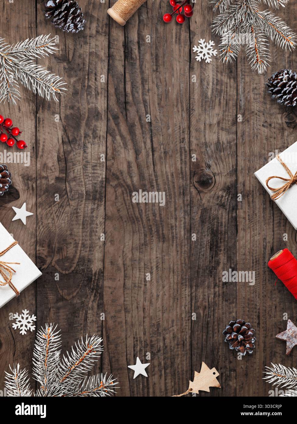 Piatto natalizio con sfondo in legno con rami di pino naturale, bacche rosse, stelle, coni e scatole regalo, spazio per testo o design Foto Stock