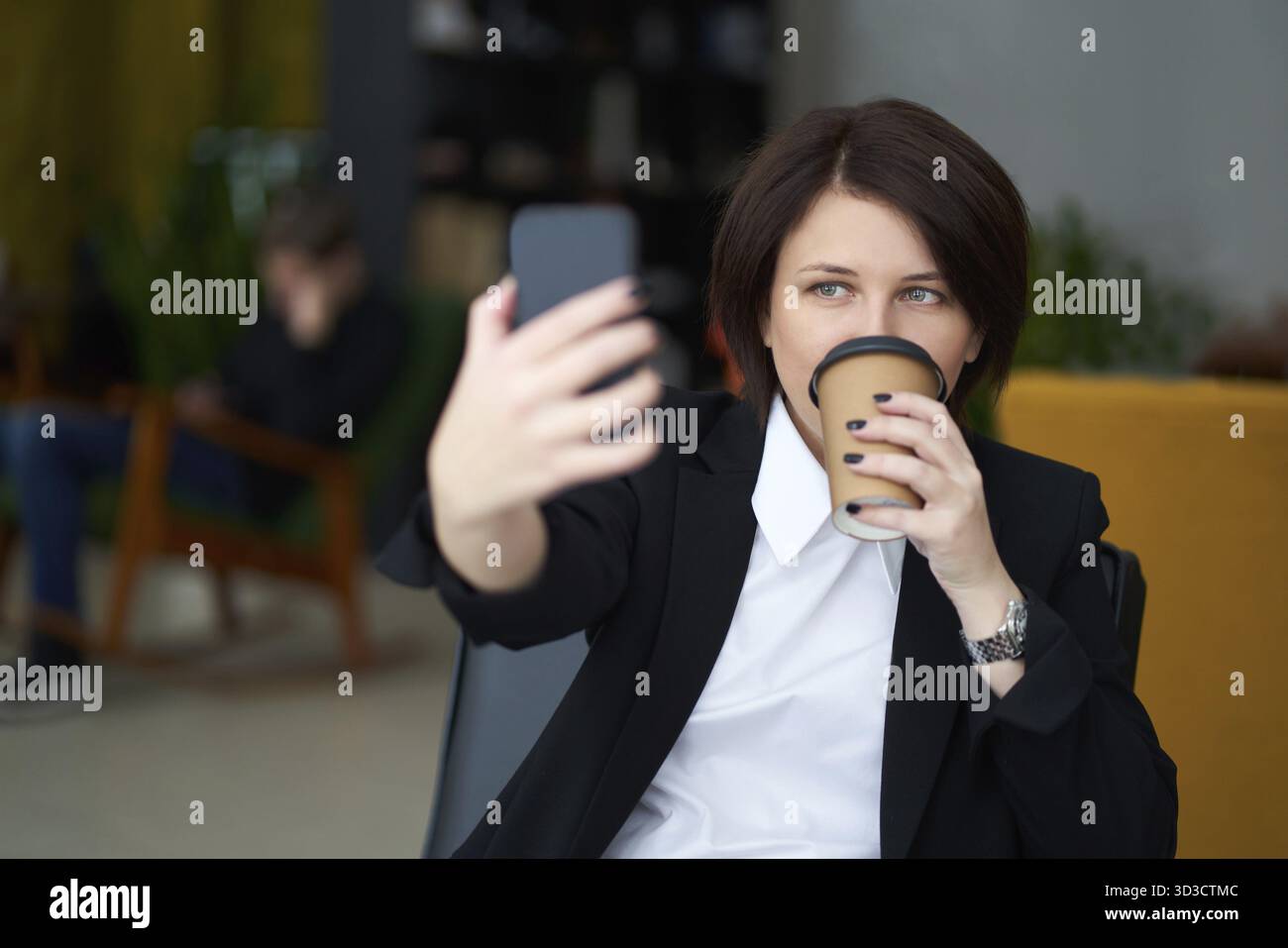Ritratto di una giovane donna d'affari caucasica in tuta che fa selfie al telefono Foto Stock