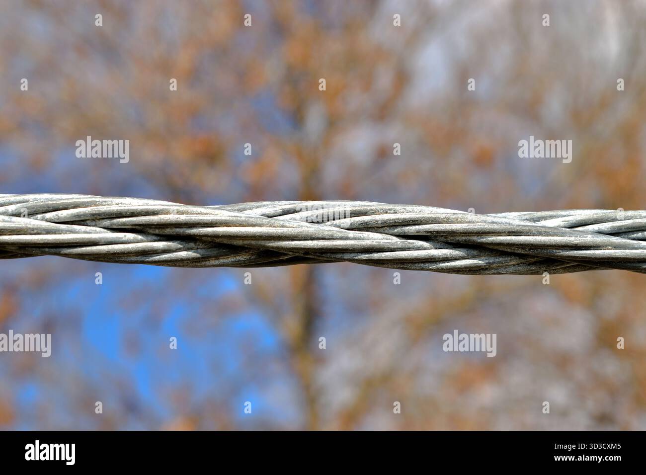 Primo piano di una fune in acciaio tesa su fondo arrugginito. La corda d'acciaio. Foto Stock