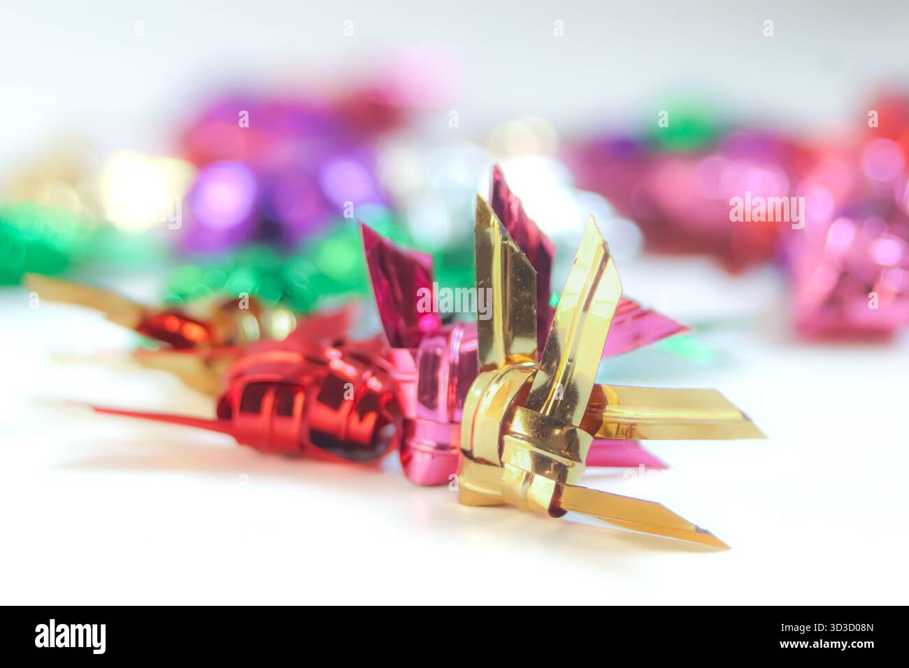 Pesce thailandese in tessuto metallico rosso, rosa e oro con vivace bokeh festivo, che combina artigianato culturale e temi di celebrazione moderni. Foto Stock