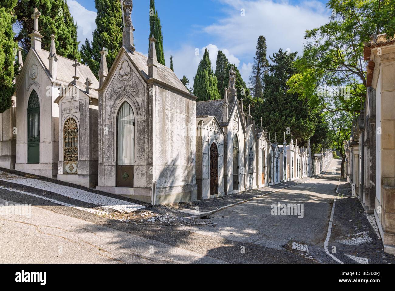 Vista laterale dei maestosi mausolei ben tenuti che costeggiano una strada tranquilla all'interno del monumentale cimitero Prazeres di Lisbona, Portogallo. Lisbona, Portogallo. 1 Au Foto Stock