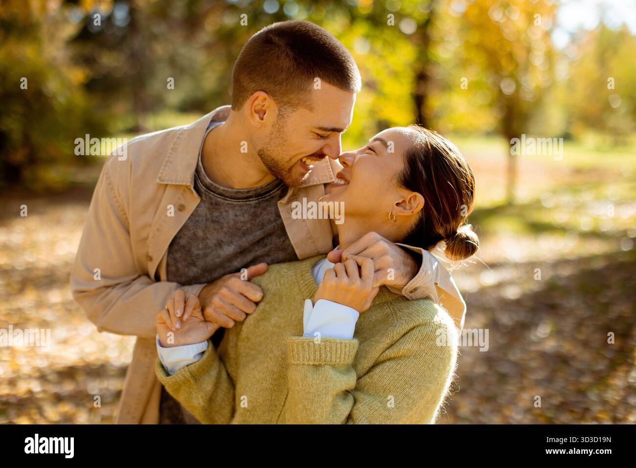 Una coppia si diverte in compagnia in un vivace parco autunnale pieno di foglie colorate. La loro connessione gioiosa è evidente. Foto Stock
