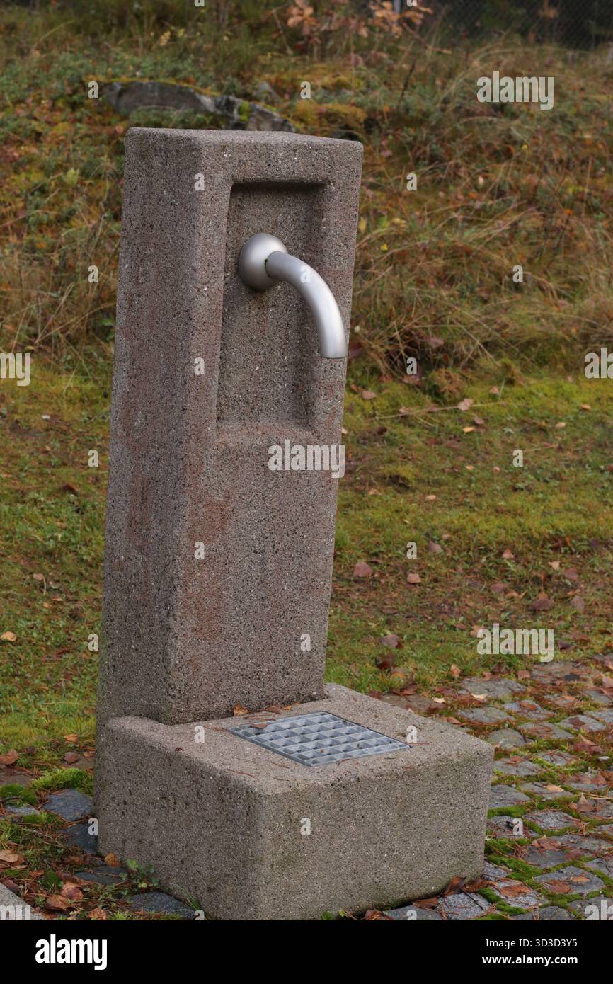 Fontana esterna di acqua potabile in pietra: Design minimalista e infrastrutture pubbliche sostenibili Foto Stock