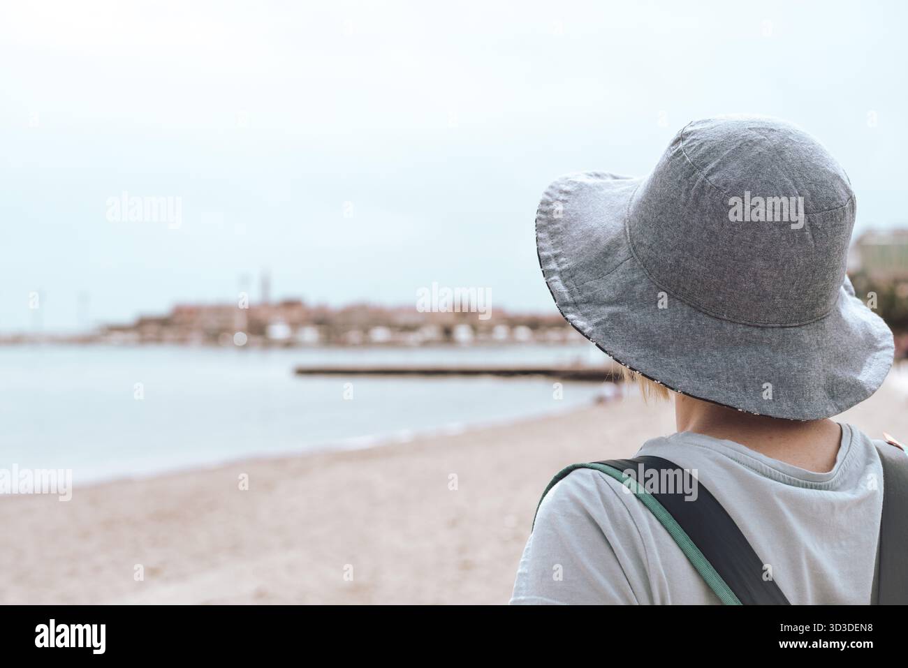 La donna caucasica con un blu hat camminando su un soleggiato lungomare in un resort estivo città di vacanze, Budva, Montenegro Foto Stock