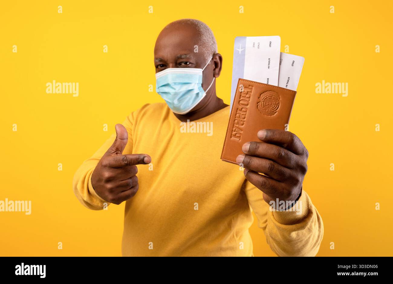 Senior Man si prepara ai viaggi internazionali durante la pandemia con biglietti e passaporto Foto Stock