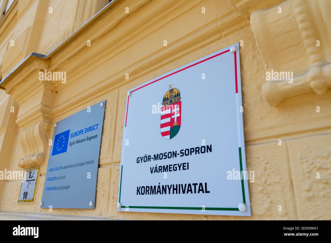 Facciata dell'ufficio governativo della contea con lo stemma ungherese e la targa Europe Direct in un edificio municipale di Győr. Foto Stock