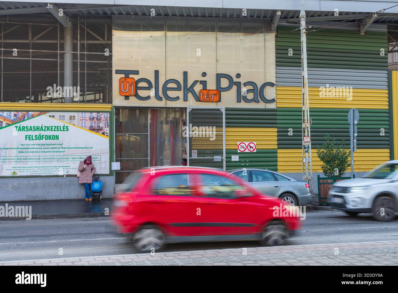 Nuovo ingresso al mercato di Piazza Teleki a Budapest, con traffico di passaggio e shopping in attesa, che cattura la vita urbana quotidiana e la cultura del mercato locale. Foto Stock