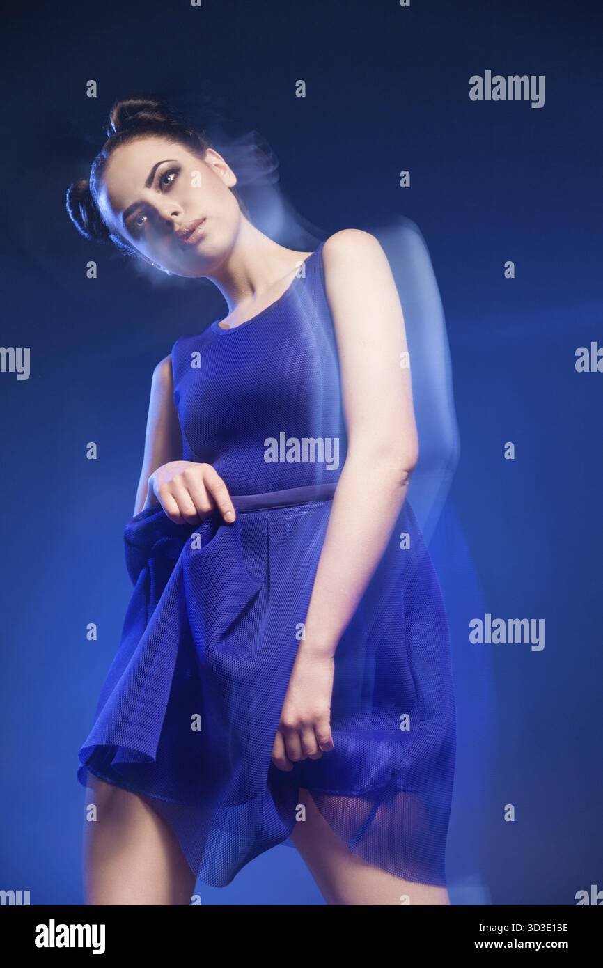 Ritratto di giovane e bella modello in posa vestito blu contro di sfondo blu.lunga esposizione Foto Stock