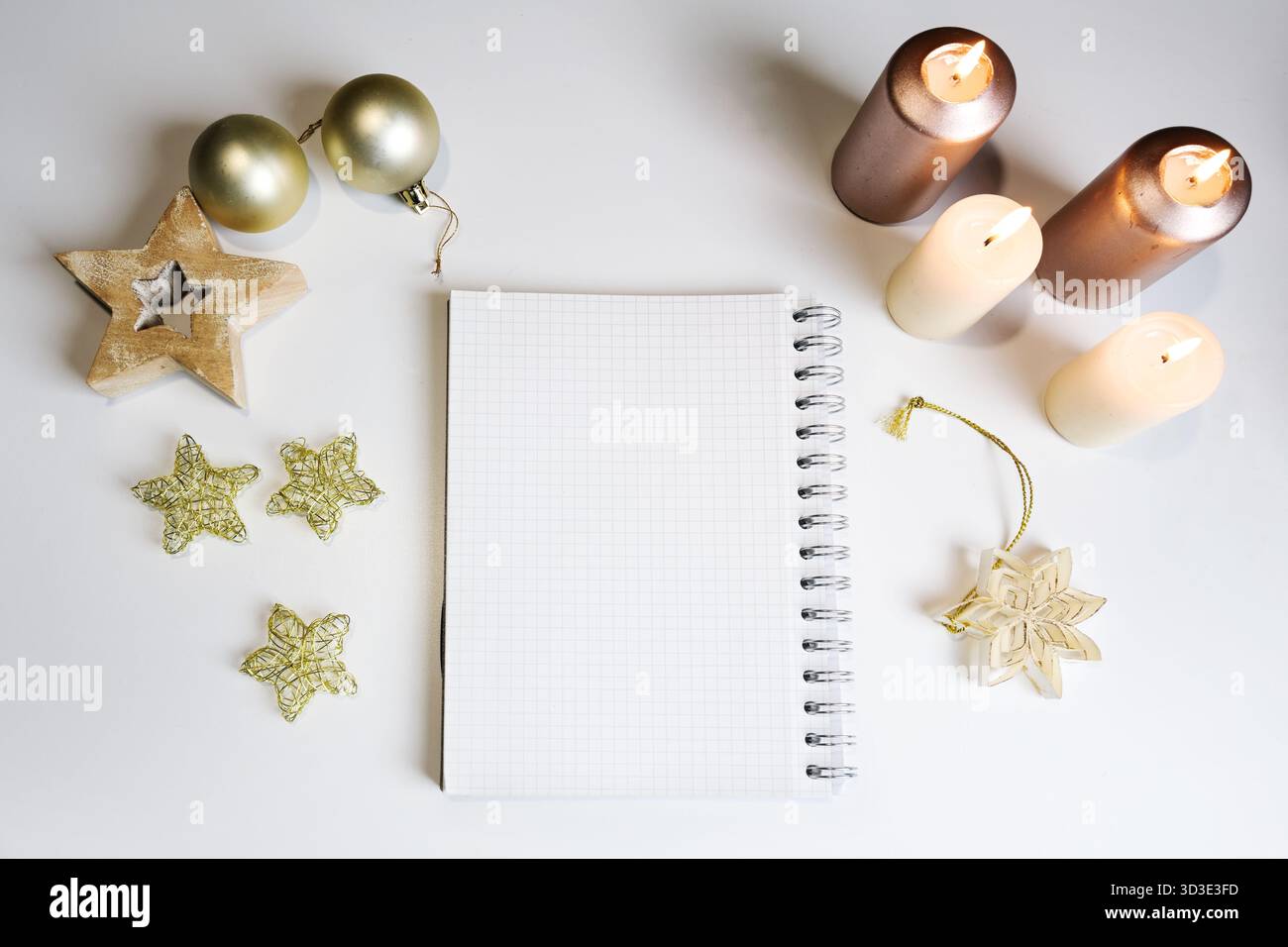 Blocco note ad anello vuoto tra quattro candele, stelle di Natale e palle, copia spazio per una lista delle cose da fare o una lista della spesa per l'avvento e le vacanze, mock-up, hig Foto Stock