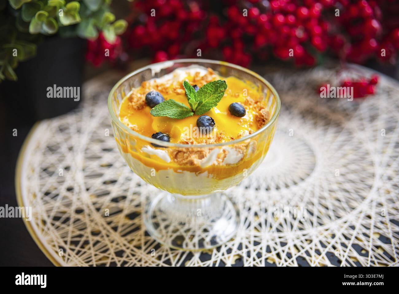 Cibo, mango rinfrescante e parfait di mirtilli conditi con panna montata, biscotti sbriciolati e foglie di menta serviti in un elegante bicchiere Foto Stock
