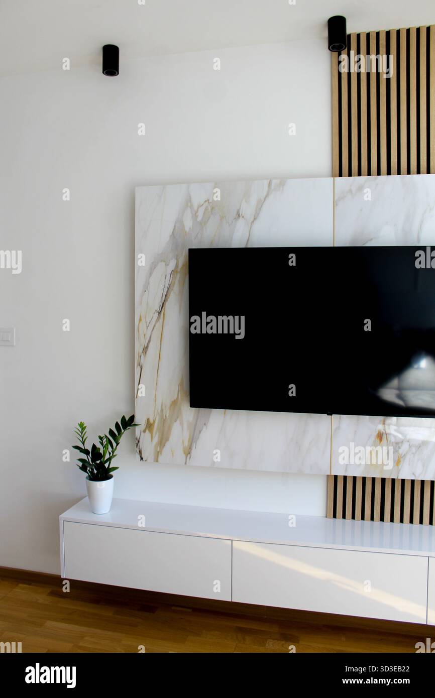 TV pulita e moderna con struttura in marmo, dettagli in legno e illuminazione soffusa che creano un'atmosfera accogliente ed elegante. Foto Stock
