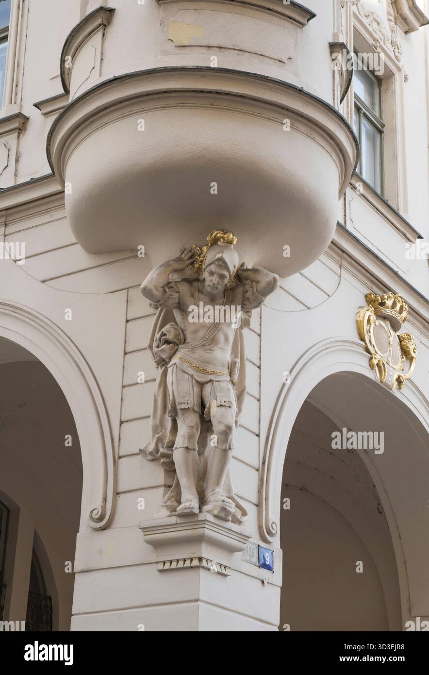 Casco dorato su una statua che sorregge una finestra di un edificio barocco. Foto Stock