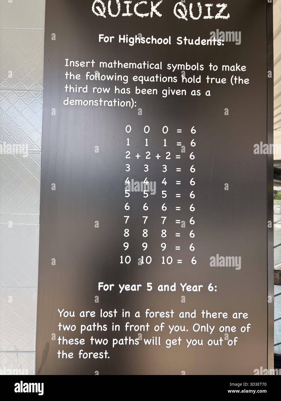 Un segno nero che mostra un "Quiz rapido" per gli studenti. Include un puzzle matematico per i liceali e un enigma per i più giovani, promo Foto Stock