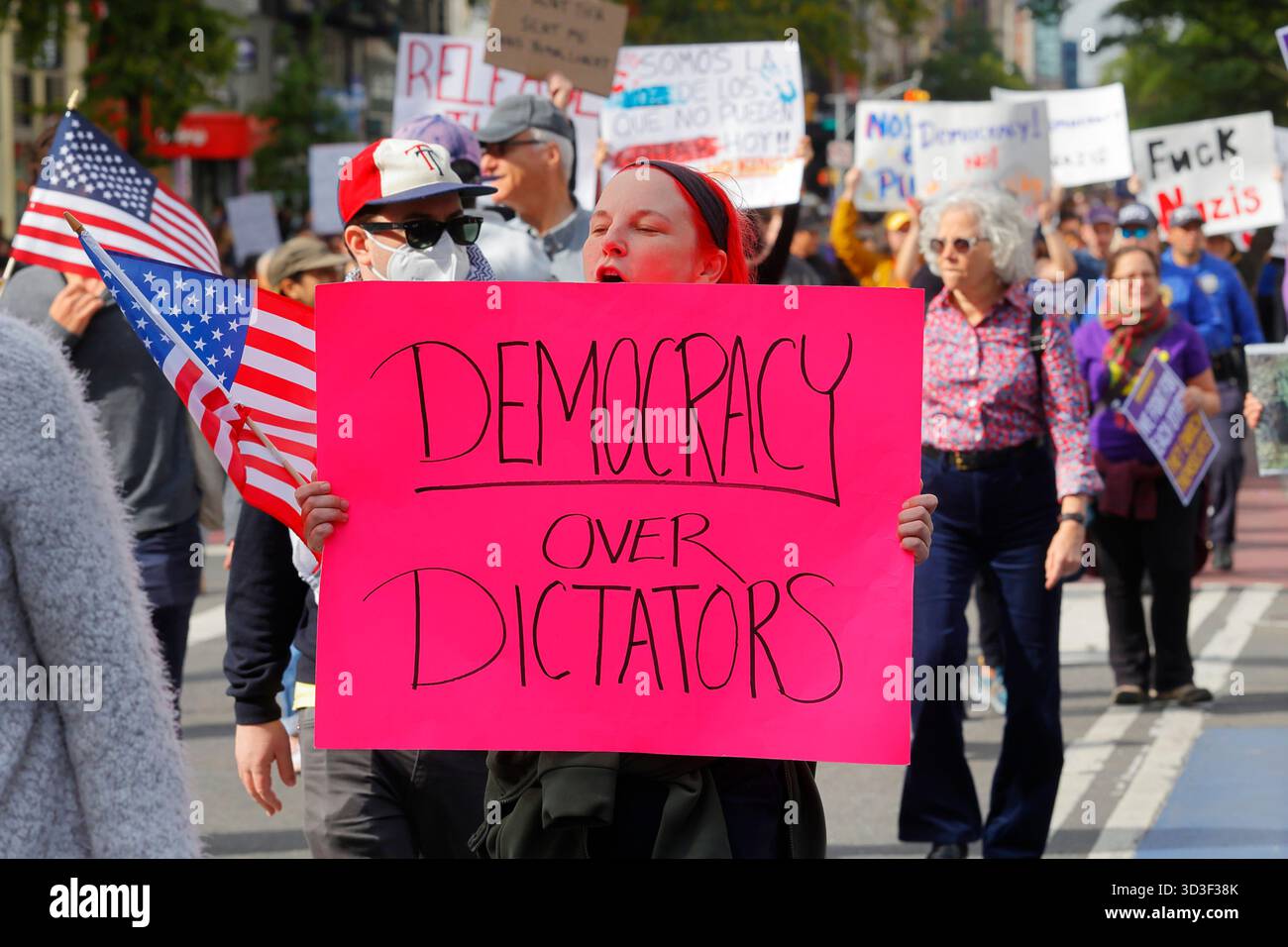 Una donna regge un cartello "democrazia sui dittatori" in una protesta contro l'amministrazione Trump, 18 ottobre 2025, New York City Foto Stock