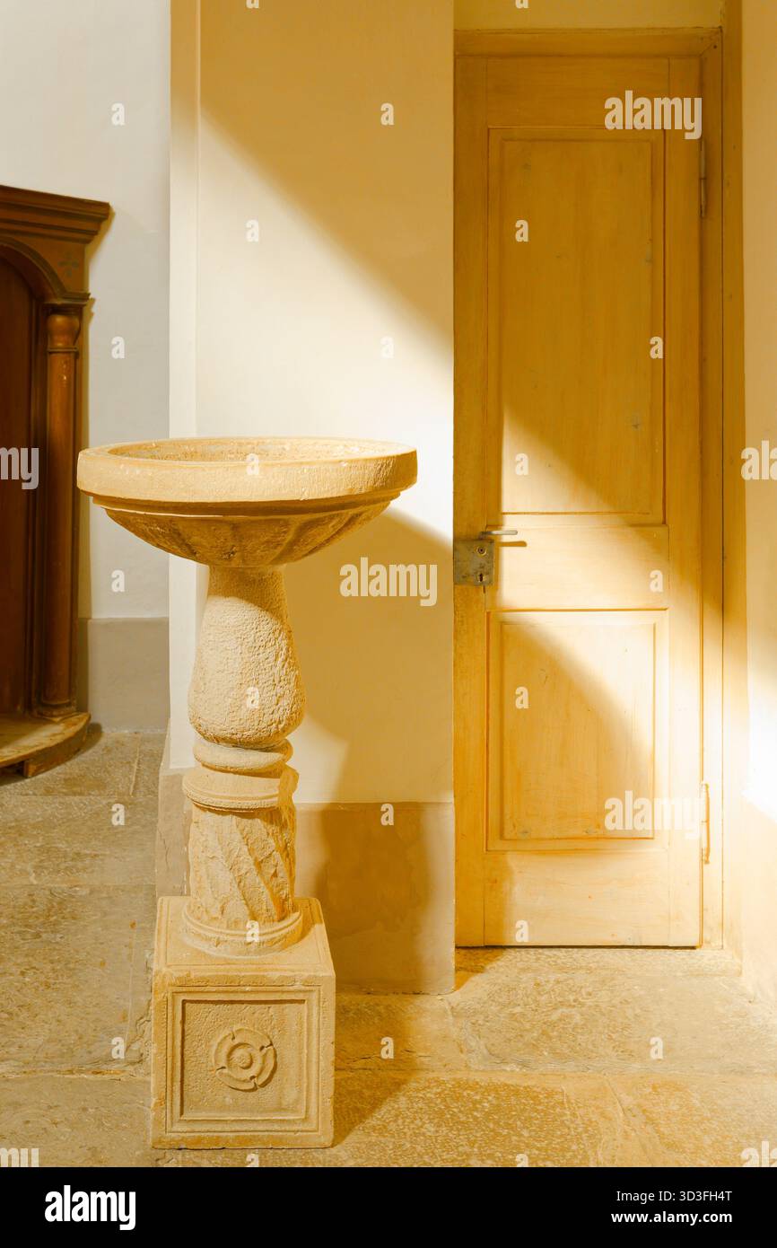 Fonte di pietra dell'acqua Santa con luce dorata, Chiesa dell'assunzione di Maria, Hum, Croazia Foto Stock