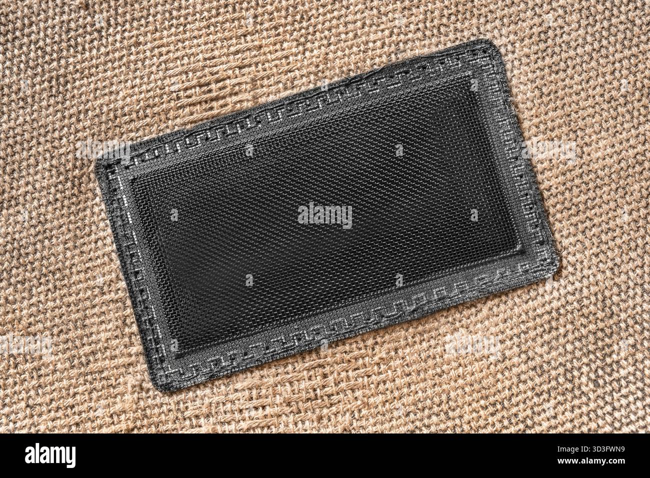 Etichetta a rete vuota cucita su sfondo in tela beige Foto Stock