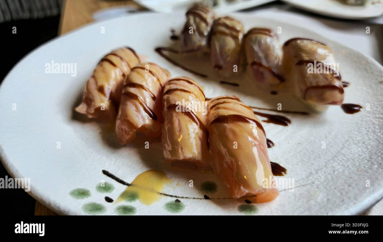 Un piatto splendidamente placcato con nigiri flambeed e salmone glassato. L'aspetto delicato e la finitura lucida lo rendono una scelta accattivante per il sughero Foto Stock