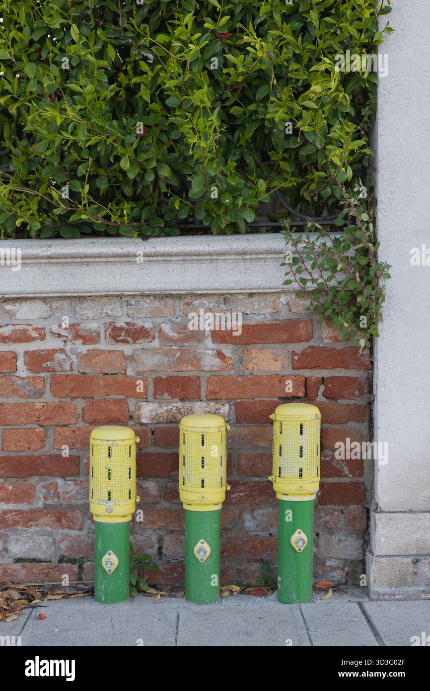 Tre prese d'acqua protette con coperchi gialli sono posizionate contro una parete in mattoni, progettate per l'uso da parte dei vigili del fuoco o dei servizi pubblici, garantendo una rapida installazione Foto Stock