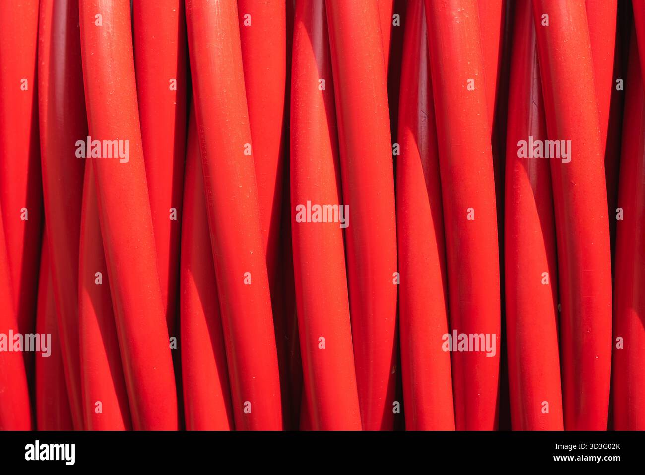Primo piano di cavi elettrici rossi luminosi disposti in modo ordinato, che mostrano i materiali essenziali utilizzati nelle costruzioni moderne e nei progetti infrastrutturali. Foto Stock