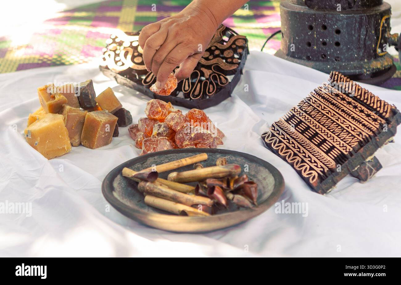 Una vista dettagliata degli strumenti e dei materiali tradizionali indonesiani per la fabbricazione del batik. Cera, francobolli e tessuto sono disposti in modo da mostrare l'intricato processo di Foto Stock