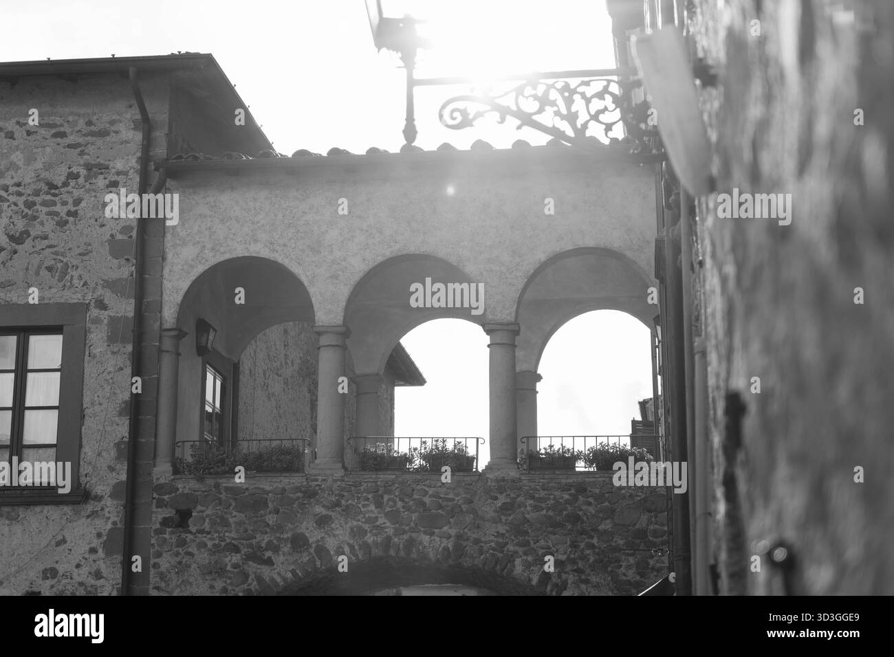 Vecchia chiesa in pietra con campanile in uno storico villaggio toscano, Italia. Fotografia di viaggio in bianco e nero che mostra la tradizionale architettura europea Foto Stock