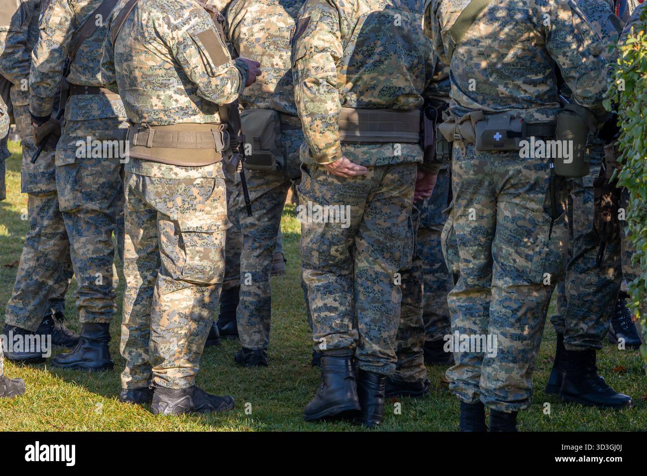 Un gruppo di soldati da dietro, parti di uniformi militari e sacchetti Foto Stock